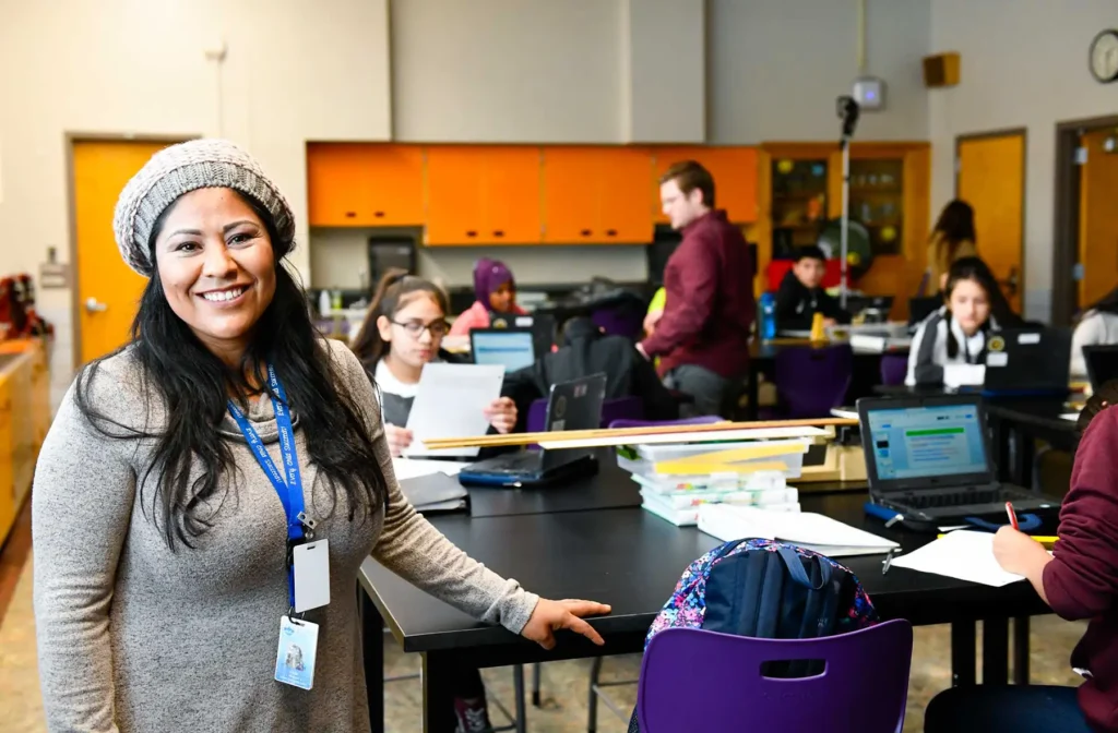 A female teacher stands in front of a high school classroom.