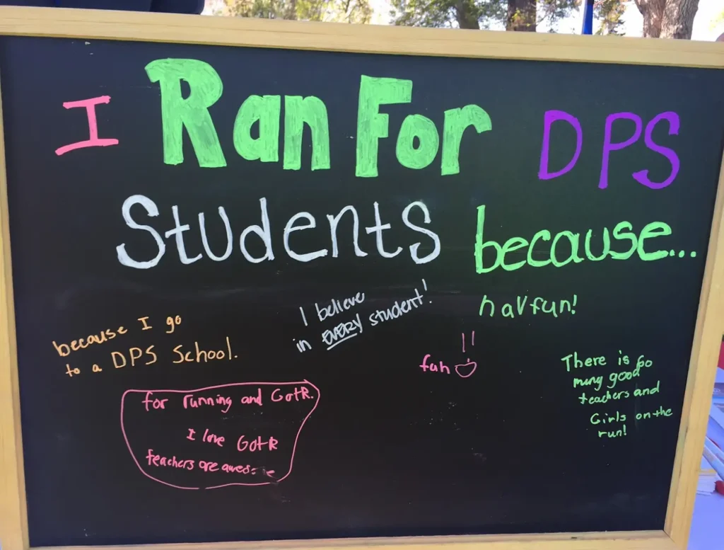 A chalkboard that reads "I ran for DPS students because... I believe in every student... fun... teachers and girls on the run."