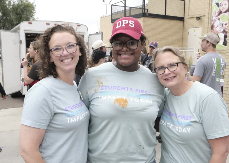 A black woman and two white women volunteer for the Back to Class Bash.