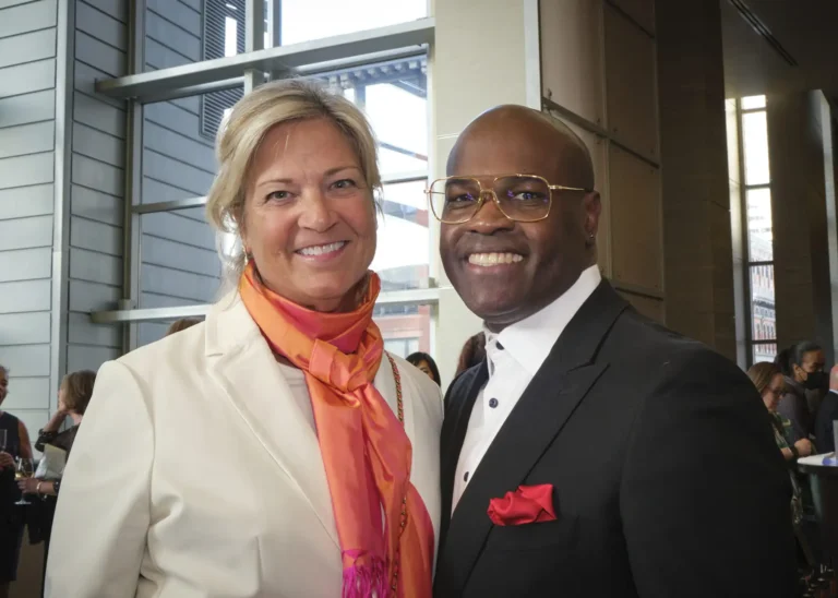 A white woman and a black man in formal attire smile together at the Achieve Gala.