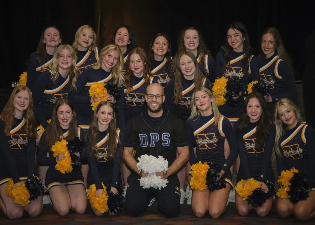 Northfield cheerleaders in uniform pose with Dr. Alex Marrero, Superintendent of Denver Public Schools.