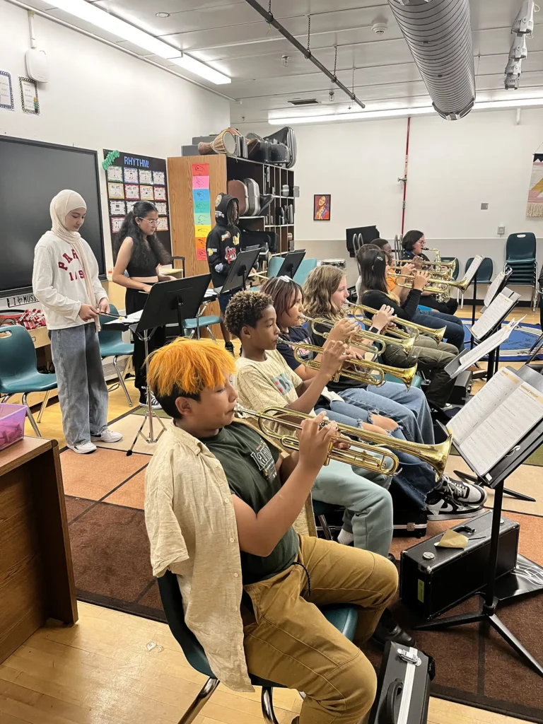 A group of young band students with trumpet players in the front row and xylophone players in the back row.