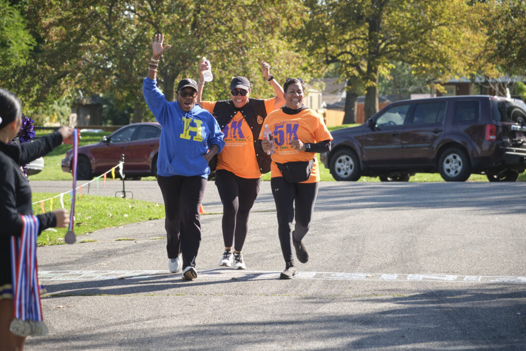 Three women cheerfully cross the finish line together.