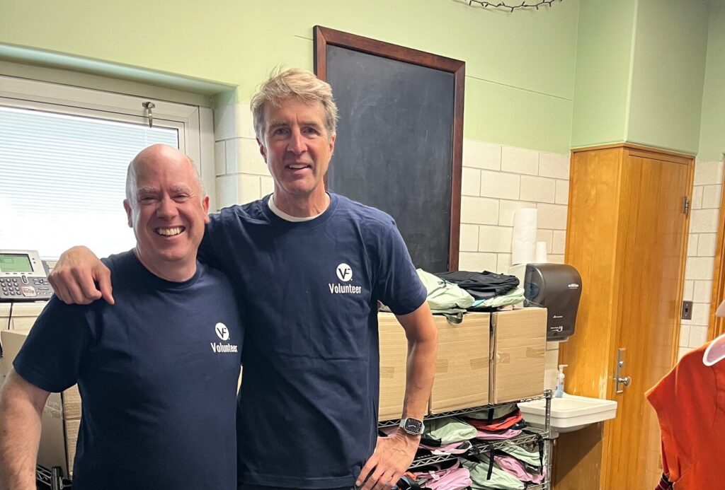 Two individuals wearing blue VF shirts smiling for the camera