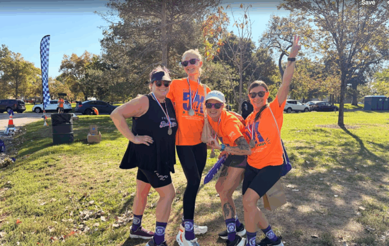 Group photo of four runners smiling while wearing their medals.