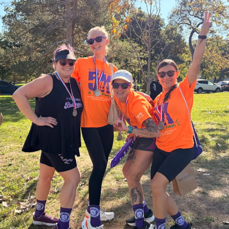 Group photo of four runners smiling while wearing their medals.