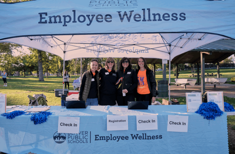 DPS Foundation staff smile together under the Employee Wellness canopy.
