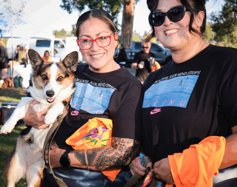 Two individuals smile for a photo while holding their dog.