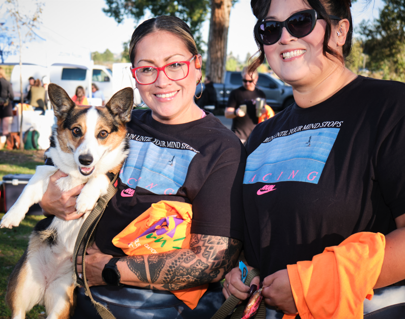 Two individuals smile for a photo while holding their dog.