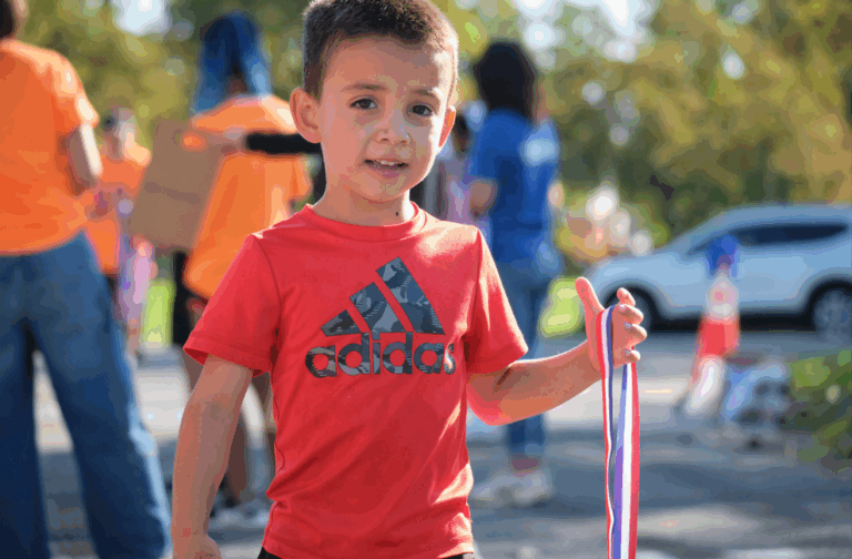 Student smiling while holding a medal in hand.