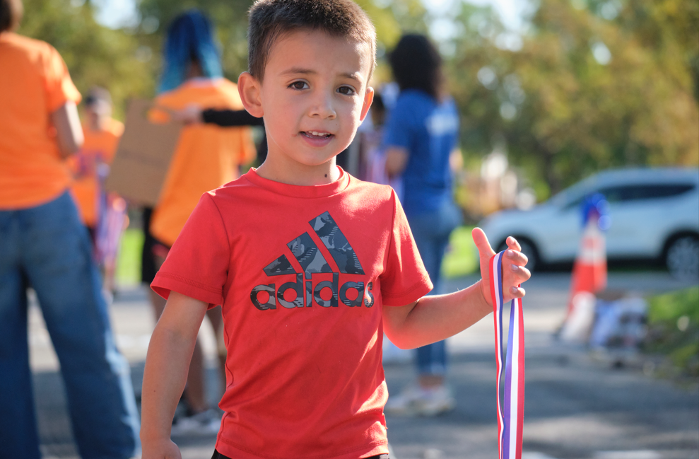 Student smiling while holding a medal in hand.
