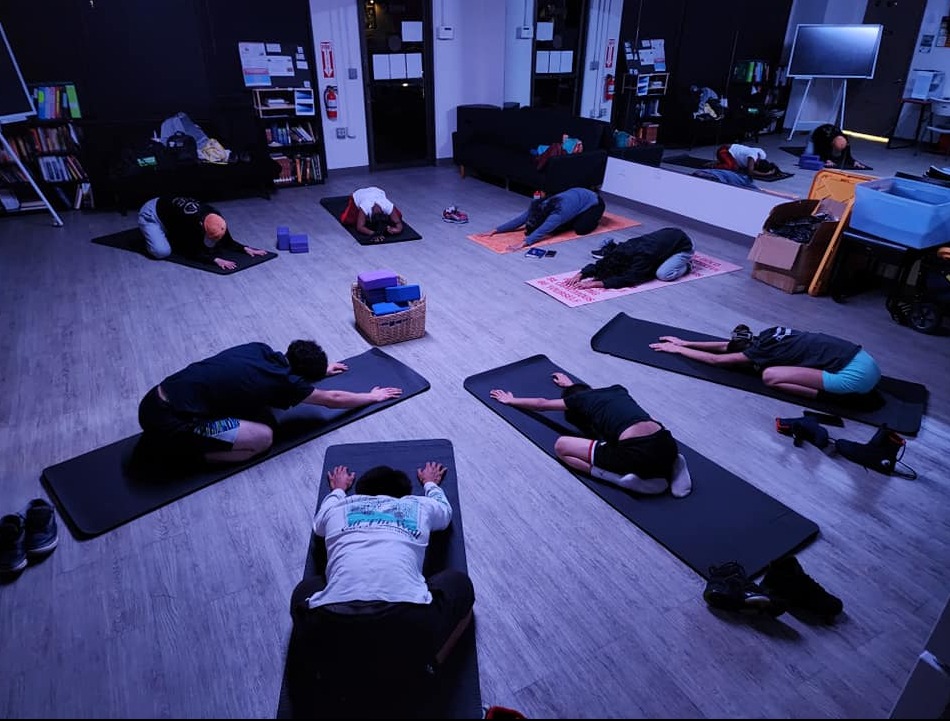 People practicing yoga on mats in a softly lit studio.