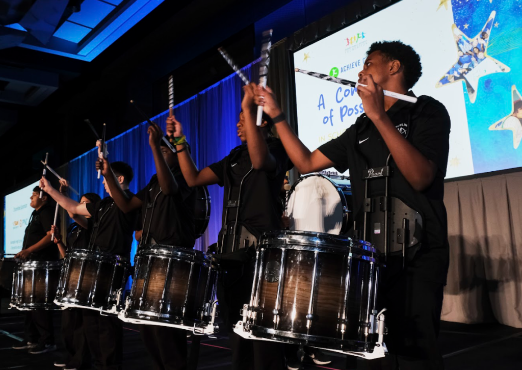 Students performing drumline routine on stage at Achieve Gala 2026.