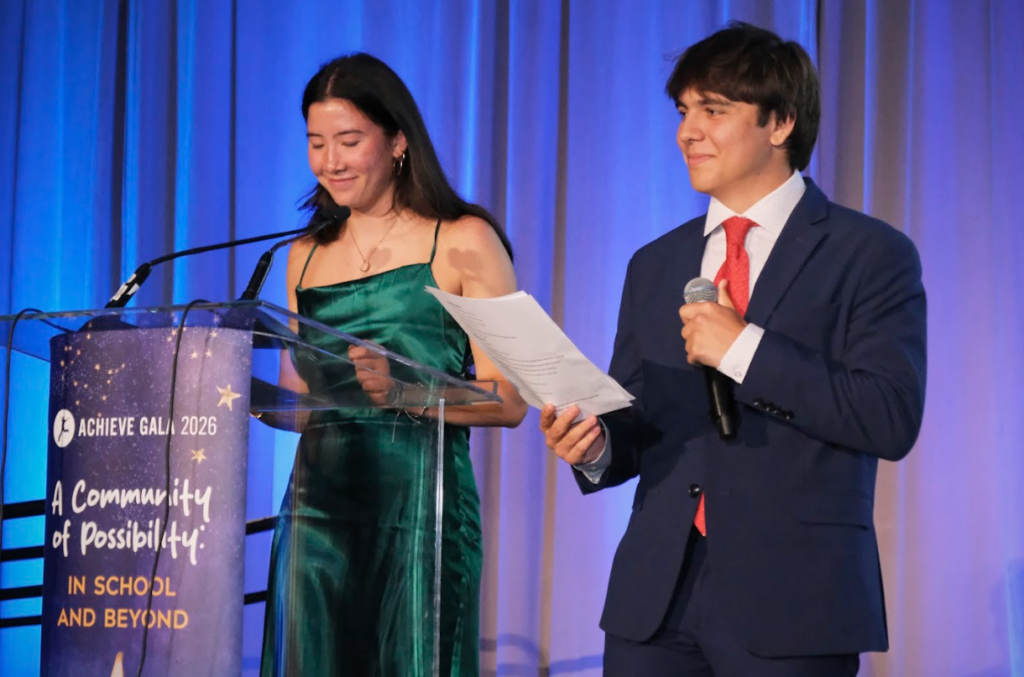 Two student emcees speaking on stage at Achieve Gala 2026.