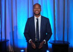 Man holding an award and smiling at Achieve Gala 2026.