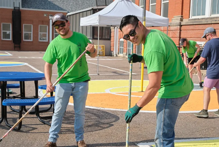 Two men volunteer to paint the concrete at a school