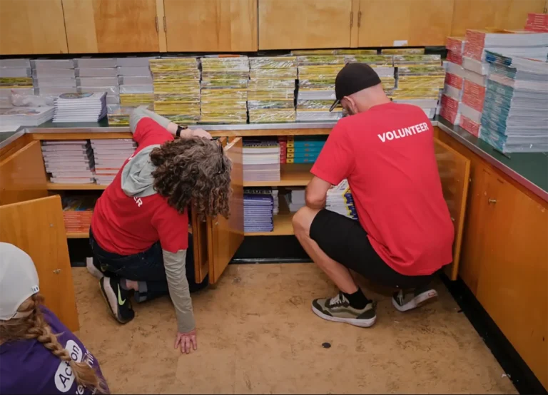 Two volunteers organize stacks of paper