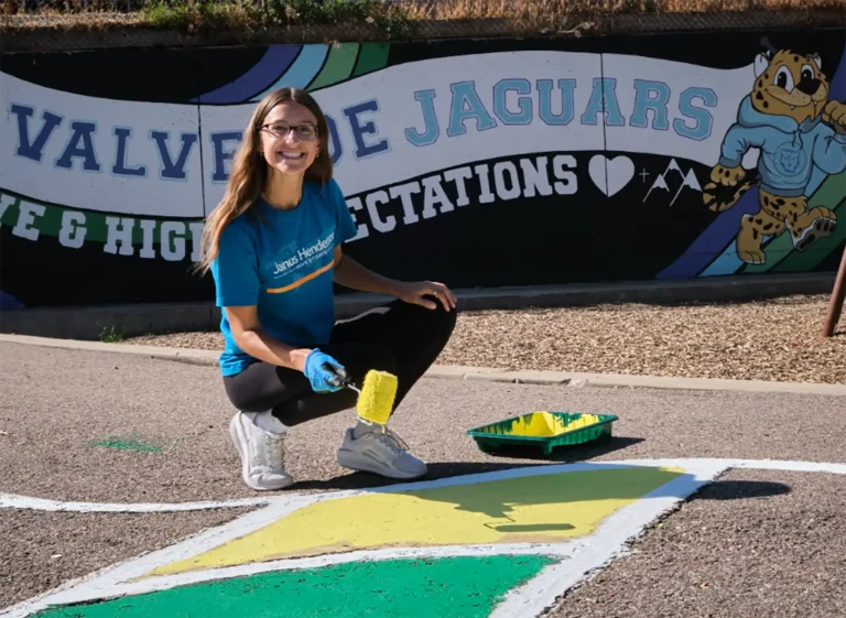 A woman paints the concrete of a parking lot of a school for the day of service